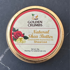 A round tin of Golden Crumbs Natural Shea Butter, featuring a gold-colored metal rim and a cream-colored label with red and gold text, set against a dark slate background.