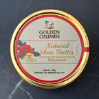 A round tin of Golden Crumbs Natural Shea Butter (Shearosé) with a gold-colored metal rim and a cream-colored label featuring a red rose and golden coconut logo, set against a dark gray marble background.