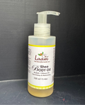A bottle of Shea Body Oil by Shea Laam, featuring a clear plastic pump dispenser and a white label with yellow accents, containing a golden-yellow oil, set against a dark gray background.